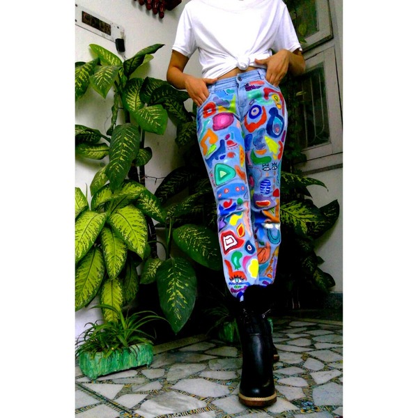 Hand-painted blue jeans with colorful graffiti artwork worn with black boots
