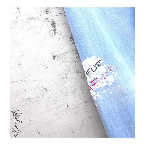 Close-up of hand-painted artwork detail on light blue denim jeans